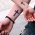 el tatuaje simetrico de pareja con una cruz en las muñecas