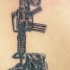 el tatuaje memorial de un m16 con una botas y un casco hecho en la espalda en color negro