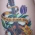 el tatuaje muy bonito de una guitarra con flores y un liston con una frase hecho en color