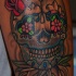 el tatuaje de una calavera mexicana con flores en sus ojos