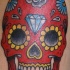 el tatuaje de una calavera mexicana roja con un diamante en su frente