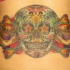 el tatuaje muy detallado dcon calavera mexicana para dia de muertos hecho en la espalda