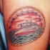 El tatuaje de un barco en el mar hecho dentro de un circulo de tracería