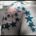 Tracería con estrellas en tinta azul tatuaje en el hombro