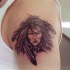 el tatuaje de una mujer india con plumas en el cabello hecho en el hombro