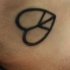 el tatuaje minimalista del simbolo de paz en forma de corazon