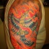 el tatuaje de la ave fenix resucitando de fuego hecho en color en el hombro
