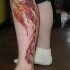 el tatuaje de la ave fenix hermosa de color negro con naranja hecho en la pierna
