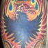 el tatuaje de un ave Fenix con una corona en las llamas de fuego hecho en el hombro