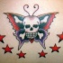 el tatuaje de una calavera sobre una mariposa con estrellas alrededor hecho en color