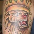 El tatuaje de la cabeza de un leon enojado con una corona hecho en color