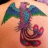 el tatuaje muy colorado y detallado de un Fenix hecho en la espalda