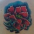 Tatuaggio colorato sulla spalla il papavero stilizzato