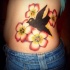 Tatuaje en el costado golondrina entre las flores en color