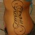 Tatuaggio sul fianco la scritta a lettere calligrafiche