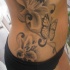 Le tatouage de flanc avec un papillon et des belles orchidées en noir et blanc