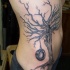 Le tatouage de flanc avec un gros arbre noir avec une roue pendante