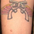 Tatuaje dos pistolas con las alas en el brazo