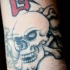Tatuaje de maligna calavera con los huesos cruzados y jeroglífico rojo