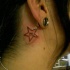 Pequeño tatuaje con la estrella y signo zodiacal detrás de la oreja