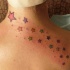 el tatuaje femenino de muchas estrellas coloradas sobre la espalda