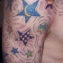 Tatuaggio colorato sul deltoide le stelle & le stelline