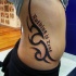 Le tatouage de flanc avec un motif en style noir avec une inscription