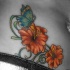Tatuaggio impressionante sulla pancia la farfalla sui  fiori aranciati