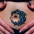 Interesante tatuaje en tinta azul en forma de la luna alrededor del ombligo