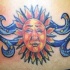 Pequeño símbolo del sol aspecto humano tatuaje en color en el bajo de  la espalda
