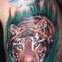 Tatuaje del tigre entre las hojas verdes