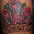 Tatuaggio colorato sulla gamba le rose e la scritta 