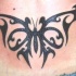 Bonito tatuaje de la mariposa tribal en el bajo de la espalda
