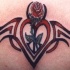 Pequeño tatuaje el signo tribal con el corazón y la rosa en tinta roja y negra