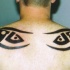 Tatuaje tribal en forma de los ojos en la espalda