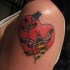 el tatuaje de un corazon rojo con una flor y una abeja hecho en el hombro