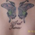 Tatuaje en la espalda mariposa cruzada en color con una inscripción
