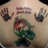 Le tatouage sur le haut du dos avec des empreintes de mains et des chats près de fleurs