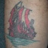 Pequeño tatuaje en color la nave  de los vikings en el fuego