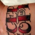 Inscripción en negro y rojo tatuaje en la muñeca