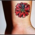 Tatuaggio colorato sul polso il papavero stilizzato