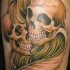 Tatuaje en el brazo, dos cráneos con plumas