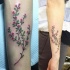Tatuaje en el antebrazo, planta delicada con flores diminutas