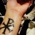 Tatuaje en la muñeca, símbolo  Chi Rho grueso negro