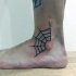 Thin dark black ink spiderweb fragment tattoo on ankle
