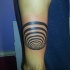 Tiny black ink arm tattoo of hypnotic symbol