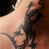 El tatuaje tribal de una lagartija en color negro y rojo hecho en el cuello