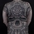 Typical large whole back tattoo of ancient human skull stylized with various ornaments and eye