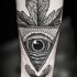 Tatuaje en el antebrazo,
ojo misterioso con hoja de arce, diseño monocromo