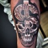 Unusual colored dollar money symbol with human skull tattoo on forearm